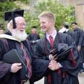 A graduate laughs with a professor as they prepare for Commencement